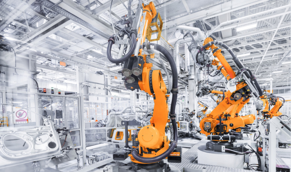 Orange industrial manufacturing robots in factory setting representing advanced automation and cost reduction solutions